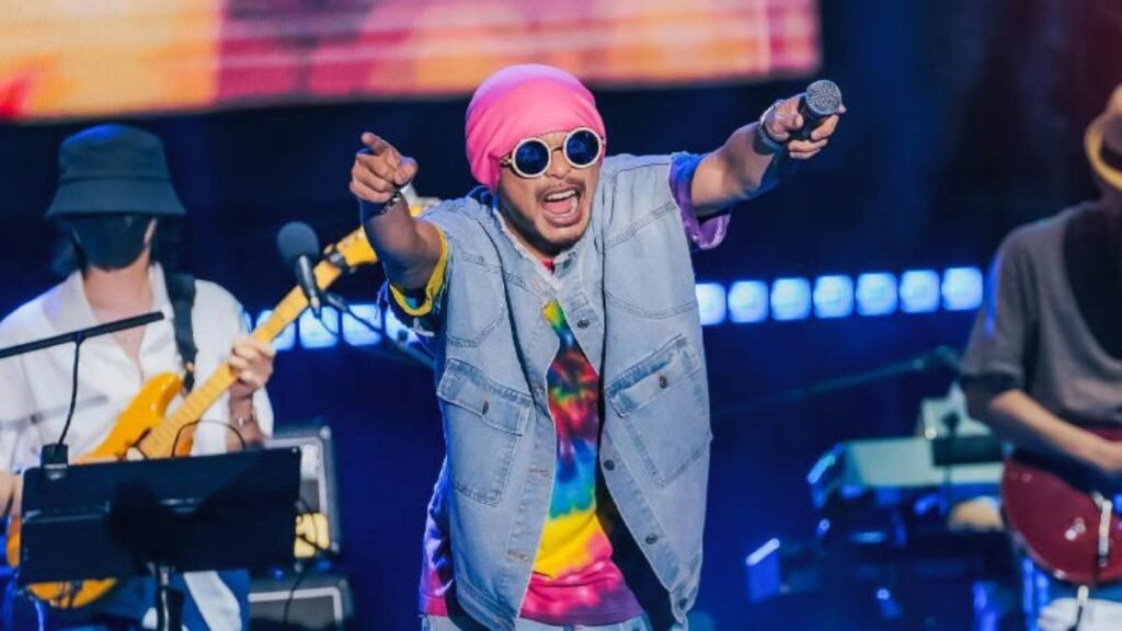 Namewee performing live on stage during a rap concert with microphone and crowd in background